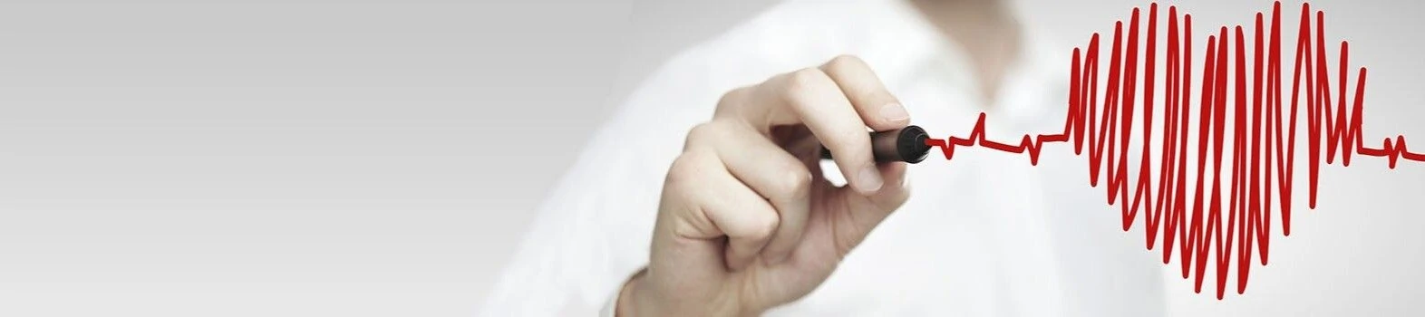 A hand is drawing a red heartbeat line on a light gray background. A hand is drawing a red heartbeat line on a light gray background.